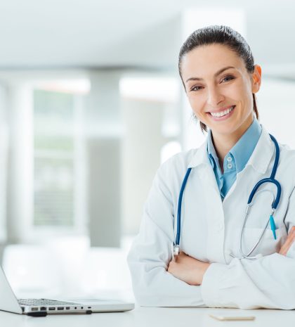 42512210 - confident female doctor sitting at office desk and smiling at camera, health care and prevention concept